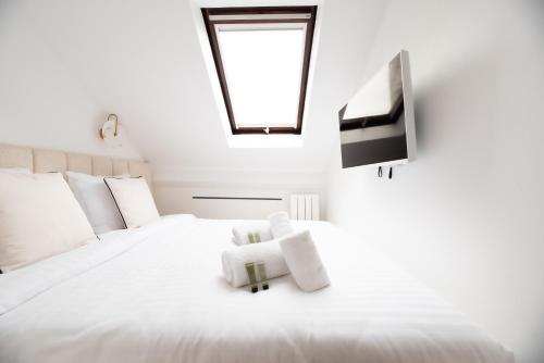 un lit blanc avec un ours en peluche assis sur lui dans l'établissement CIA - Modern Flat, Galeries Lafayette, à Paris