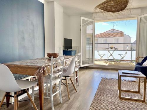une salle à manger avec une table et des chaises et une grande fenêtre dans l'établissement Falaise - Saint Gilles Croix de Vie, à Saint-Gilles-Croix-de-Vie