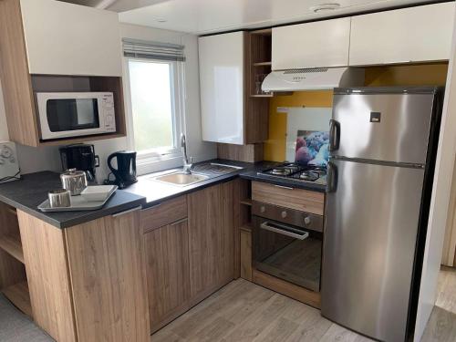 une cuisine avec un réfrigérateur en acier inoxydable et des armoires en bois dans l'établissement 731 du bois Dormant Saint Jean de Monts, à Saint-Jean-de-Monts