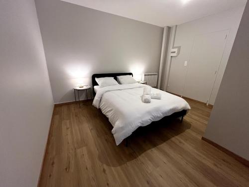 Cette chambre comprend un lit avec des draps blancs et du parquet. dans l'établissement Bienvenue à l'Oustalet Appt 5, à Cazaubon