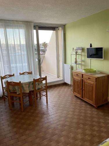 un salon avec une table, des chaises et une télévision dans l'établissement Studio Héliopolis K114 - 4 personnes, au Cap d'Agde