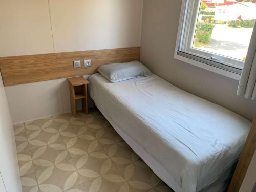 une petite chambre avec un lit et une fenêtre dans l'établissement 745 du bois Dormant Saint Jean de Monts, à Saint-Jean-de-Monts