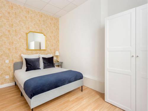 une chambre avec un lit et un miroir au mur dans l'établissement Merveil - Family Suite - Marais - Martin III, à Paris