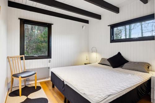 une chambre avec un lit, une chaise et une fenêtre dans l'établissement Cozy Nature Getaway Just Minutes From Ebeltoft And Top Attractions, à Ebeltoft