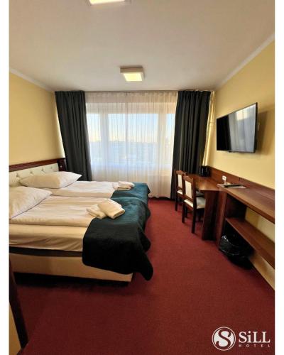 a hotel room with two beds and a desk at Hotel SiLL in Kielce
