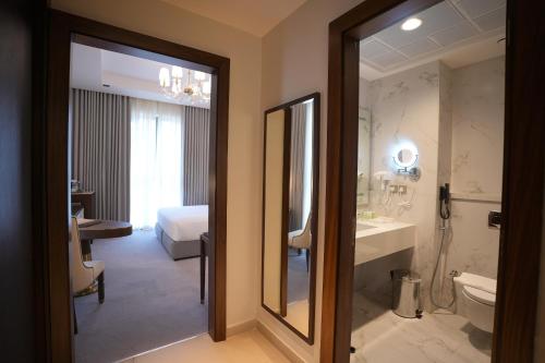 a bathroom with a toilet and a sink and a mirror at Peninsula Worth Hotel in Al Madinah