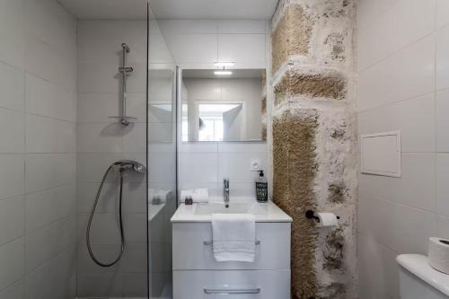 a white bathroom with a sink and a shower at La Maison d'Or in Saint-Cyr-au-Mont-dʼOr
