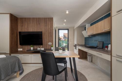a kitchen with a table with chairs and a television at Balaton Flow Residence in Fonyód