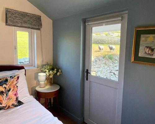a bedroom with a bed and a window with sheep outside at Gwyneska in Llanaber