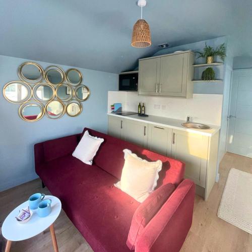 a living room with a red couch and a kitchen at Gwyneska in Llanaber