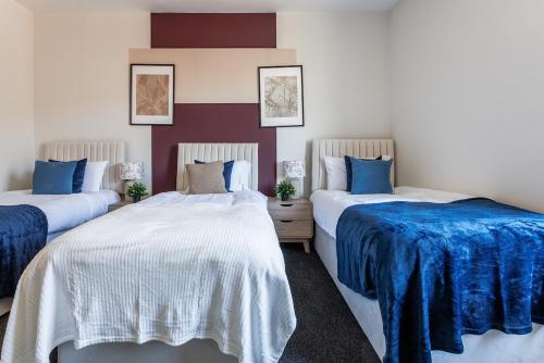 ビショップ・オークランドにあるCharming Central 3BR Home Near Auckland Castleの青と白のシーツが敷かれた部屋にベッドが2つある