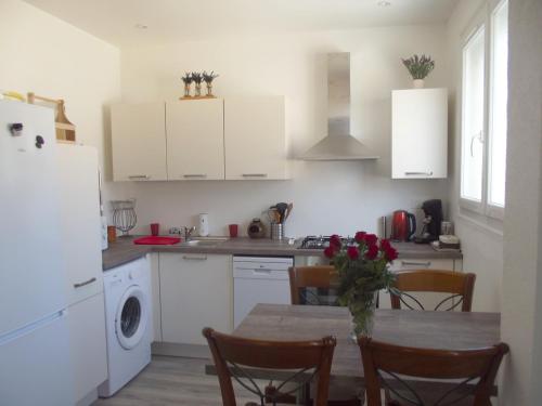 une cuisine avec des armoires blanches et une table avec des chaises dans l'établissement Appartement indépendent dans villa au cœur du Var, à Gonfaron