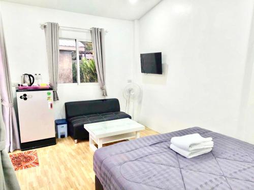a room with a bed and a couch and a refrigerator at Cina Home in Chiang Mai
