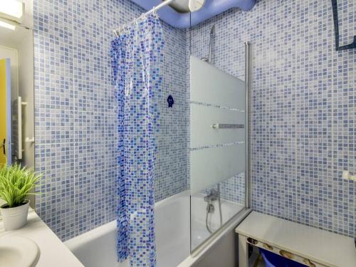 La salle de bains est pourvue d'une baignoire et d'une douche avec du carrelage bleu. dans l'établissement Appartement 8 pers au pied des pistes, La Mongie - FR-1-404-131, à La Mongie