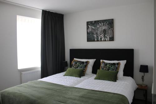 a bedroom with a bed with two green pillows at Studio SIS - Aparthotel in Steenbergen