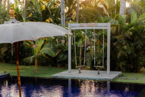an umbrella next to a swimming pool next to a resort at La Royale Nusa Penida in Nusa Penida