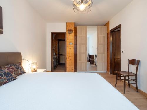 a bedroom with a large white bed and a chair at Residence Valtellina - Appartamento centrale vicino salita Baradello in Le Bratte