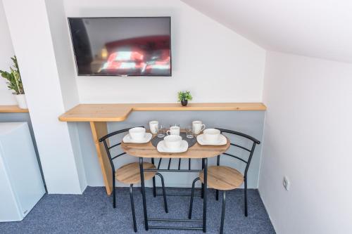 a small table with chairs and a tv on a wall at Penzion Ronox in Česká Skalice