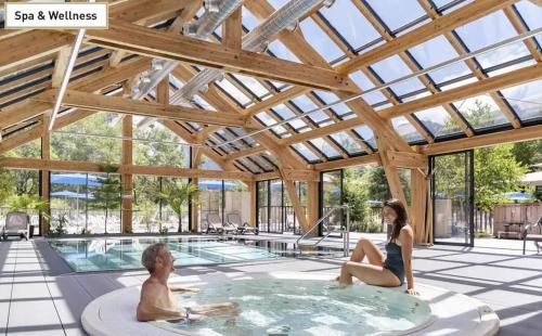 un homme et une femme assis dans un bain à remous dans une maison dans l'établissement Chalet Familial au bord du lac, à Doussard