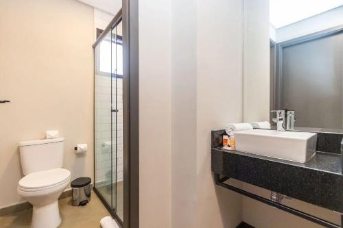 a bathroom with a white toilet and a sink at Vibe Curitiba by Housi, próximo à Ligga Arena e Praça do Japão in Curitiba