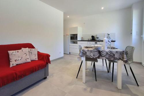 un salon avec une table et un canapé rouge dans l'établissement Appartement avec terrasse à Santa Maria Poggio, à Santa-Maria-Poggio