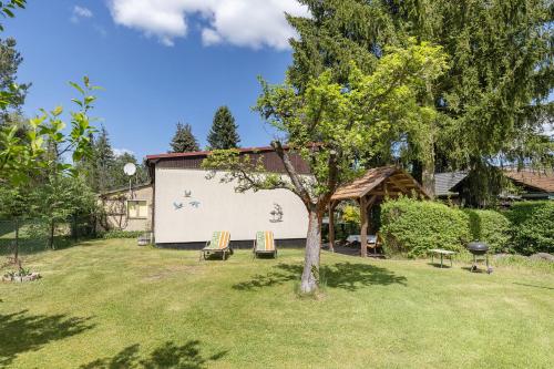a building with chairs and a tree in a yard at Ferienwohnung am Bloschk in Schwielochsee