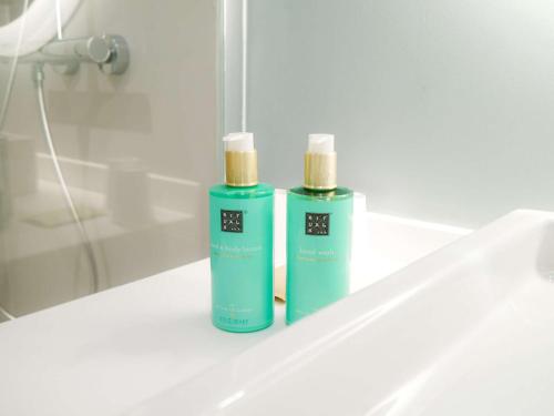 two green bottles ofodorizers sitting on a bathroom sink at Novotel Monte-Carlo in Monte Carlo