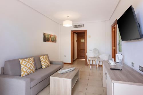 a living room with a couch and a flat screen tv at Landmar Costa los Gigantes Family Resort in Puerto de Santiago
