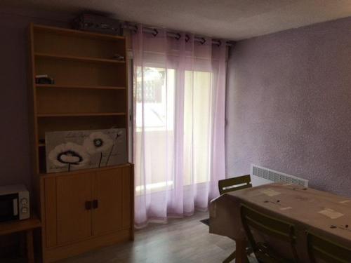 Cette chambre dispose d'une table et d'une fenêtre avec des rideaux. dans l'établissement Studio Cabine 4 Pers. - Balcon, Parking Couvert, à 50m des Pistes - FR-1-404-209, à La Mongie