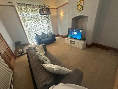 a living room with a couch and a tv at Spacious House- Parking Garden & Central Location in Walsall