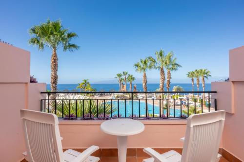 a balcony with a table and chairs and a pool at Landmar Costa los Gigantes Family Resort in Puerto de Santiago