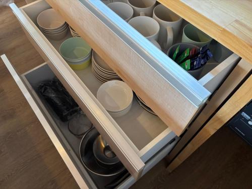 a drawer filled with cups and plates in a kitchen at 簡易宿所 51ハウス 音と温泉 みんなで時間を楽しむ貸切一軒家 in Shiraoi