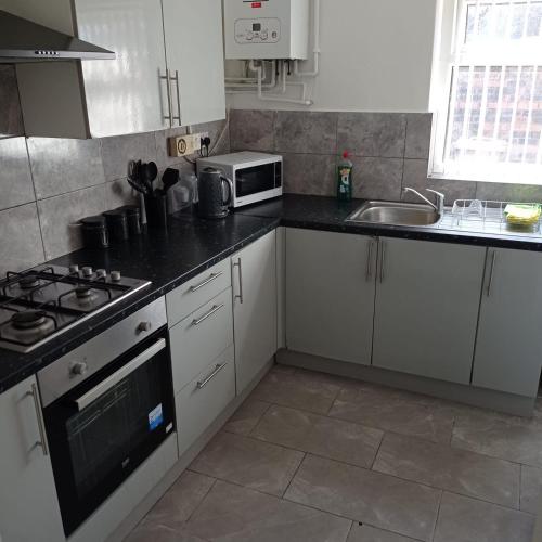 a kitchen with white cabinets and a stove top oven at Double-Bedroom in the Heart of Salford Manchester Perfect for Short Stays LT2 in Manchester