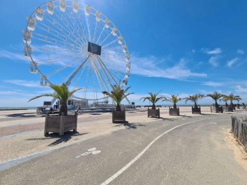 une grande roue ferris sur une plage bordée de palmiers dans l'établissement Studio rénové, 2 couchages, mer, commerces, 6e étage, TV, balcon, animaux admis - FR-1-224C-138, à Saint-Jean-de-Monts