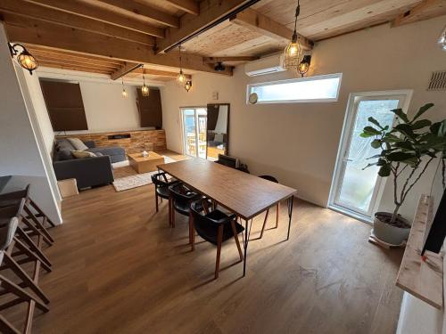 a dining room and living room with a table and chairs at 簡易宿所 51ハウス 音と温泉 みんなで時間を楽しむ貸切一軒家 in Shiraoi