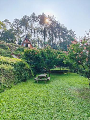 a picnic table in a field with trees and a house at Sentral Camp in Pengalengan
