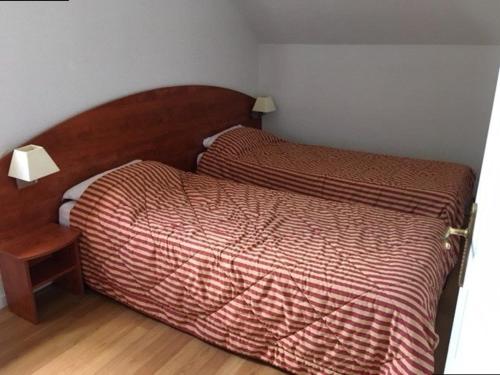- une chambre avec 2 lits et une tête de lit en bois dans l'établissement Duplex avec Piscine, Salle de Fitness, Parking et Animaux Acceptés - FR-1-404-321, à Bagnères-de-Bigorre