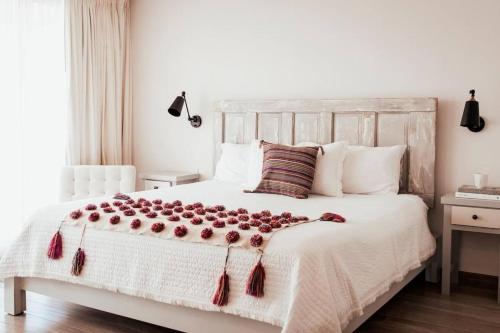 a bedroom with a white bed with red tassels on it at Villas Ensueño - Valle De Guadalupe in San Antonio de las Minas