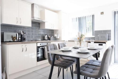a white kitchen with a table and chairs at Contemporary 3 Bedroom Home with Garden & Parking in Atherton