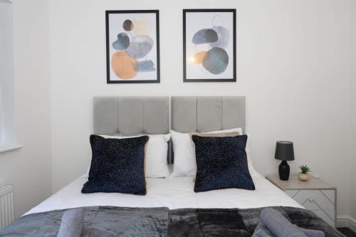 a bedroom with a bed with four pictures on the wall at Contemporary 3 Bedroom Home with Garden & Parking in Atherton