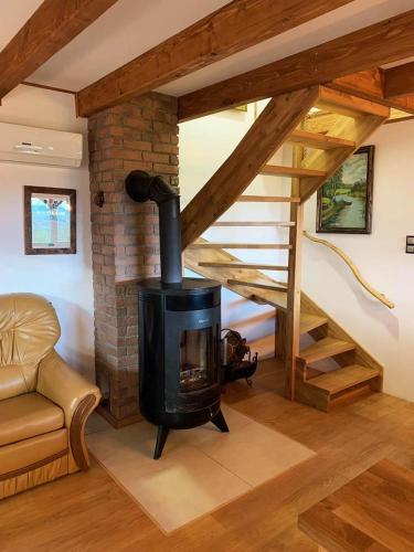 a living room with a wood stove and a staircase at Domek Letniskowy Zielone Tarasy z Sauną i Jacuzzi in Korczyna