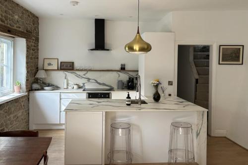 a white kitchen with a counter and stools at 3 Bed Cottage - Sleeps 6 - Pets - Parking - Wifi in Petworth