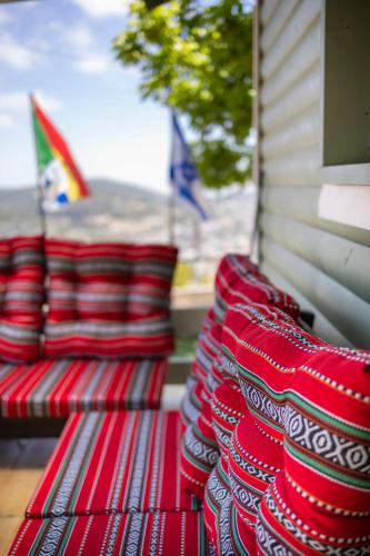 a row of red pillows sitting on a bench at בקתות עץ מעל העננים - אירוח דרוזי - בקתות כפריות עם נוף מהמם ובריכה משותפת in Bet Dagan