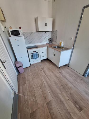 Il comprend une petite cuisine avec des appareils blancs et du parquet. dans l'établissement Appartement 2eme étage, à Saint-Dizier
