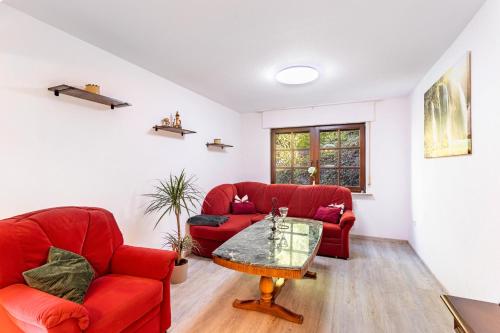 a living room with two red chairs and a table at Haus Waldesruh in Medebach