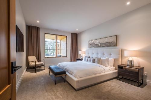 a bedroom with a large white bed and a chair at Havre Ride-Out 113 Luxurious & Modern Direct Ski-in Ski-out in Mont-Tremblant