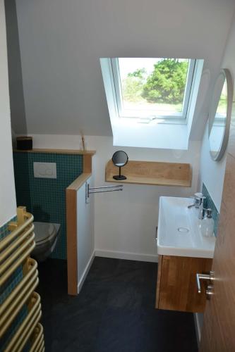 La salle de bains est pourvue d'un lavabo et de toilettes avec une fenêtre. dans l'établissement Le clos de la lande vallée, à Bringal