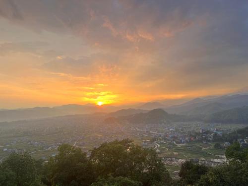 a sunset over a city with mountains in the background at Hotel Lekhnath View Tower and Eco Farm in Deorāli