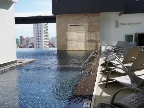 a swimming pool on the side of a building with chairs at Naki Suites @ Silvertown in Phnom Penh