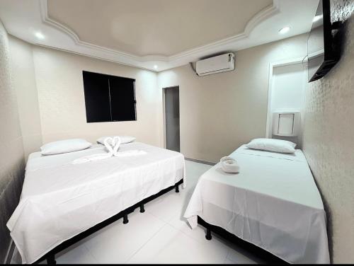 a room with two beds and a flat screen tv at Basic Hotel Praia in Aracaju